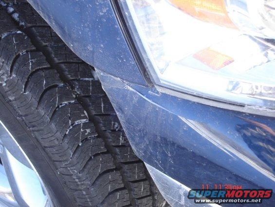 Blue vehicle's front tire and headlight assembly, close-up