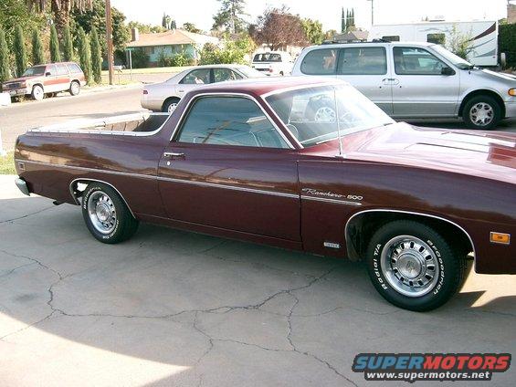 Maroon 1970 Ford Ranchero 500 pickup truck parked on driveway, other vehicles in background