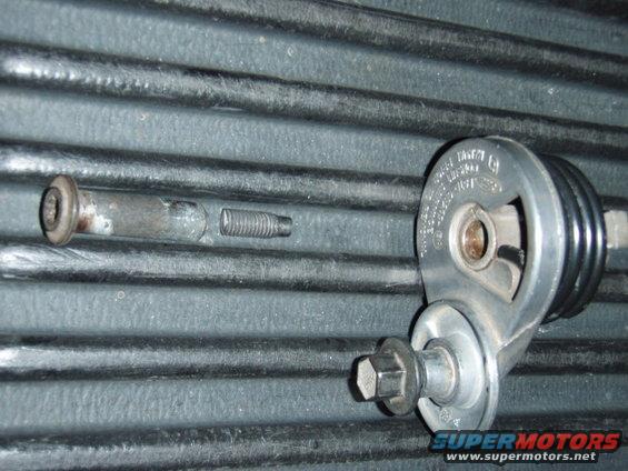 Belt tensioner pulley assembly with two bolts on a ribbed surface