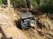 1976 Ford Bronco - This off-road SUV navigates a challenging, muddy terrain with steep inclines and exposed roots.