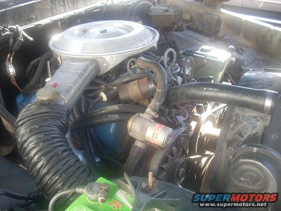 Engine bay with air cleaner, hoses, and battery visible. Some text on a filter reads 'AS'