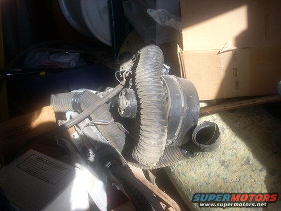 HVAC blower motor with hoses and wiring, sitting among boxes and debris