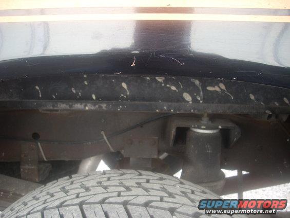 Rear suspension and tire of a vehicle with black paint and a yellow stripe