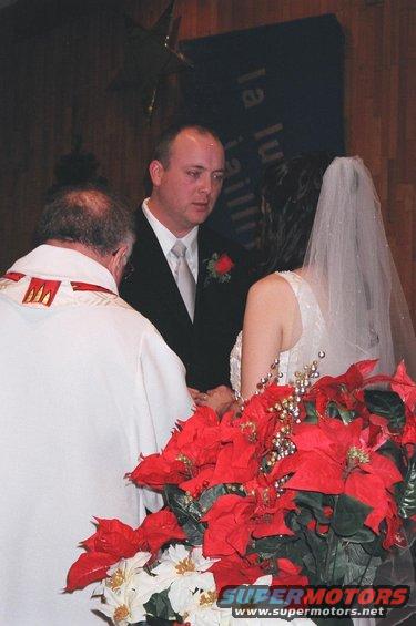 Wedding ceremony with a groom, bride, and officiant, decorated with poinsettias
