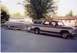 1979 Ford Bronco - A man works on the hitch of a trailer carrying a boat, which is being towed by a two-tone Ford Bronco.