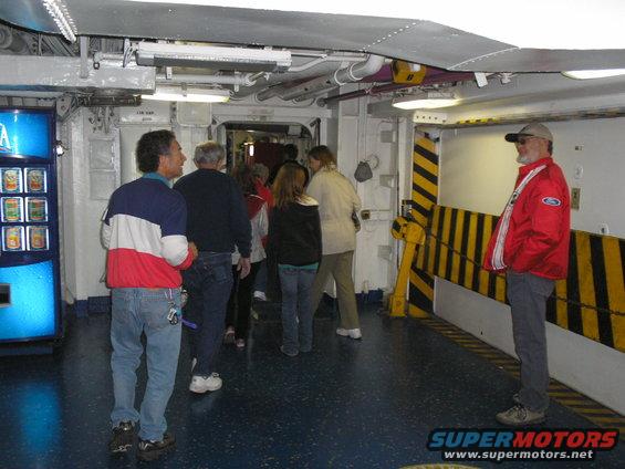 people in a hallway with a vending machine and yellow-striped caution barriers