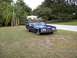 1973 Mercury Cougar - Blue 1973 Mercury Cougar convertible sits on a grassy area next to a road, with trees and a house visible.