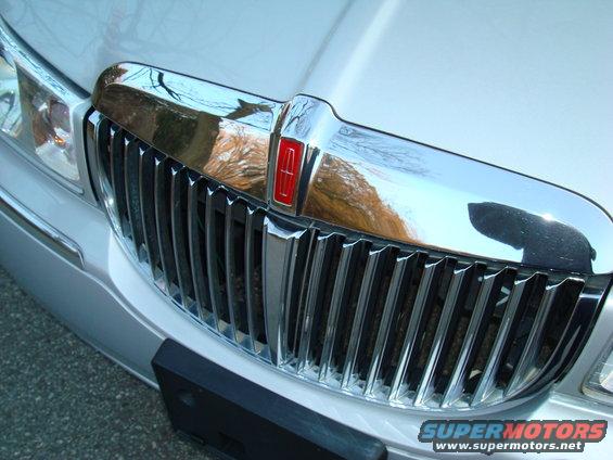 Silver Lincoln Town Car grille with chrome vertical bars and a red Lincoln emblem