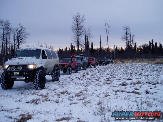 2000 Ford E350 and other off-road vehicles driving in a line through a snowy field