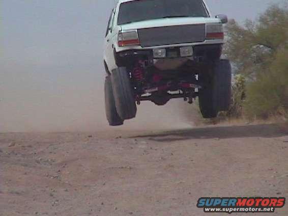 White SUV mid-air jump, lifted suspension, large tires