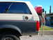1991 Ford Bronco - This 1991 Ford Bronco shows its rear quarter panel, a spare tire mounted on the back and a red cooler.