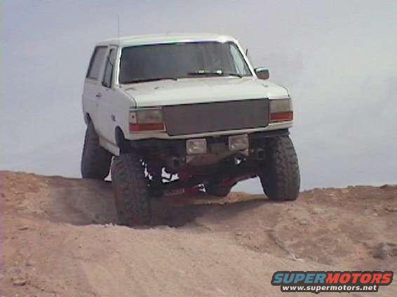 White 1992 Ford Bronco on dirt hill, front 3/4 view, lifted suspension