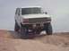 1992 Ford Bronco - White 1992 Ford Bronco with lifted suspension driving on a dirt incline.