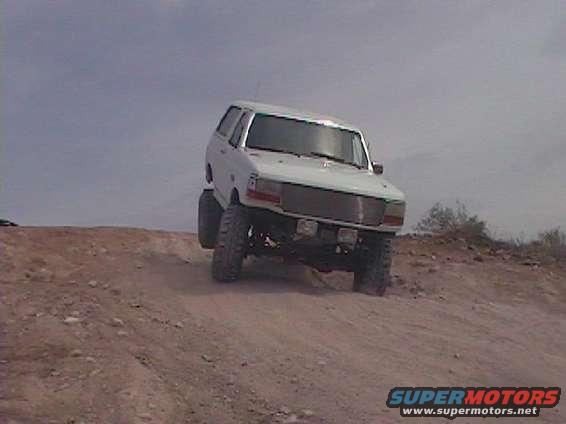 White 1992 Ford Bronco driving on a dirt hill
