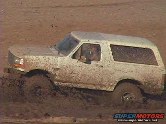 White Ford Bronco stuck in mud, side view
