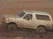 1992 Ford Bronco - This white Ford Bronco is deep in the mud, with its tires partially submerged.