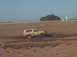 1992 Ford Bronco - A white SUV is stuck in a muddy area under a clear sky with dry terrain in the background.
