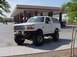 1992 Ford Bronco - White 1992 Ford Bronco with aftermarket modifications sits outside a convenience store.