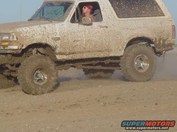 Mud-covered 1992 Ford Bronco side view driving through water