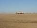 1992 Ford Bronco - A 1992 Ford Bronco kicks up dust as it travels across a barren, sandy terrain.
