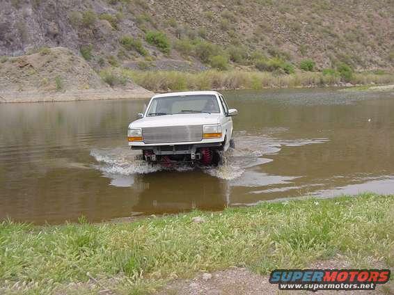 1992 Ford Bronco driving through shallow water, front view