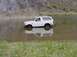 1992 Ford Bronco - A white 1992 Ford Bronco is partially submerged in water, driving towards the shore.