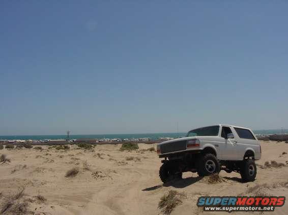 White 1992 Ford Bronco on sand dune, 3/4 front view, clear sky