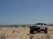 1992 Ford Bronco - A white 1992 Ford Bronco is parked on a sand dune under a clear blue sky.