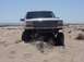 1992 Ford Bronco - This lifted 1992 Ford Bronco is shown on a sandy terrain under a clear blue sky.
