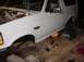 1992 Ford Bronco - The front quarter panel of a white 1992 Ford Bronco is shown with the engine compartment exposed and the vehicle raised on stands.