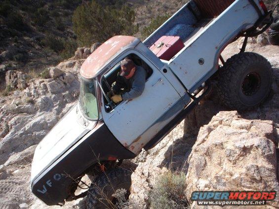 White pickup truck navigating rocky terrain, side view. Text 'WFO' visible on fender