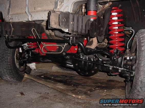 Close-up of red coil springs and black suspension parts on a vehicle