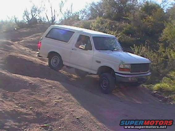 White 1992 Ford Bronco driving up a dirt hill