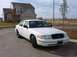 1999 Ford Crown Victoria - A white Ford Crown Victoria sedan is parked in front of a suburban house.