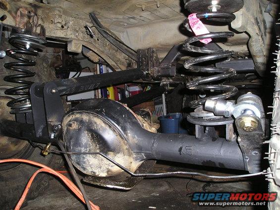 Rear axle assembly with aftermarket suspension components, including coil springs and control arms