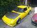 1983 Mazda RX-7 - A yellow 1983 Mazda RX-7 is parked outdoors next to other vehicles.
