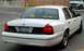 1999 Ford Crown Victoria - A white sedan is parked outdoors, with another vehicle visible in the background.