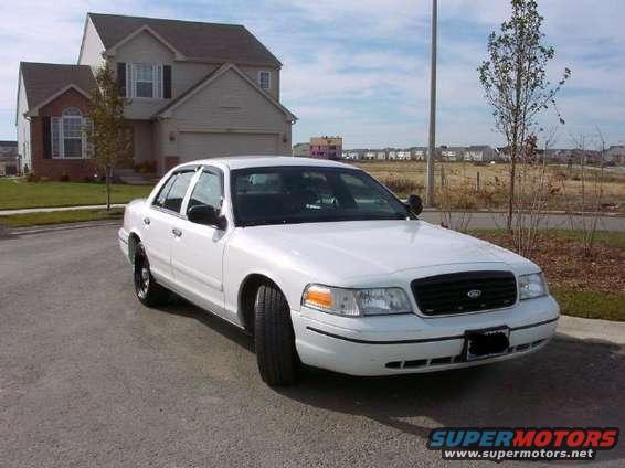 White sedan parked on asphalt, front 3/4 view. Black grille, tinted windows, black license plate