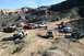 1981 Ford Bronco - A group of off-road vehicles parked on a dirt path in a mountainous desert area.