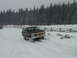 1979 Ford Bronco - A maroon Ford Bronco navigates a snowy landscape with a wooden fence and pine trees in the background.
