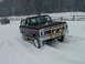 1979 Ford Bronco - A brown 1979 Ford Bronco navigates a snowy landscape, with another vehicle visible in the background.