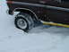 1979 Ford Bronco - A dark brown Ford Bronco is partially submerged in snow and ice, with its front wheel stuck.