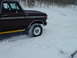 1979 Ford Bronco - A 1979 Ford Bronco navigates through a snowy landscape, kicking up snow as it drives.