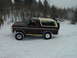 1979 Ford Bronco - A 1979 Ford Bronco navigates a snowy landscape, its two-tone paint contrasting with the wintery surroundings.