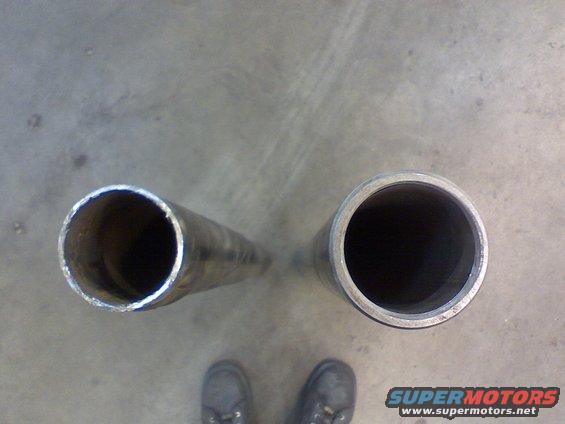Two metal pipes, one wider than the other, lying on a concrete floor