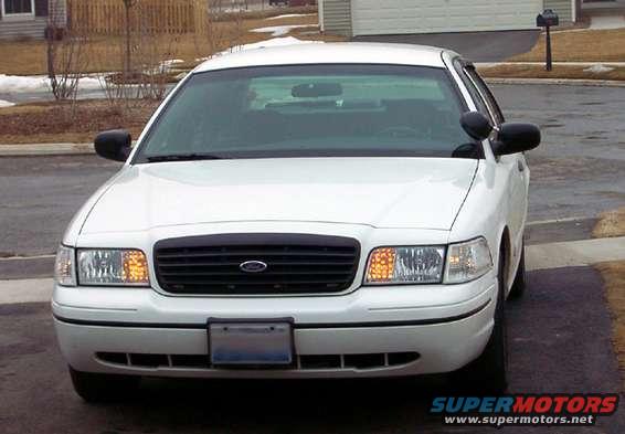 White Ford Crown Victoria, front view, with black grille and side mirrors. License plate area is visible