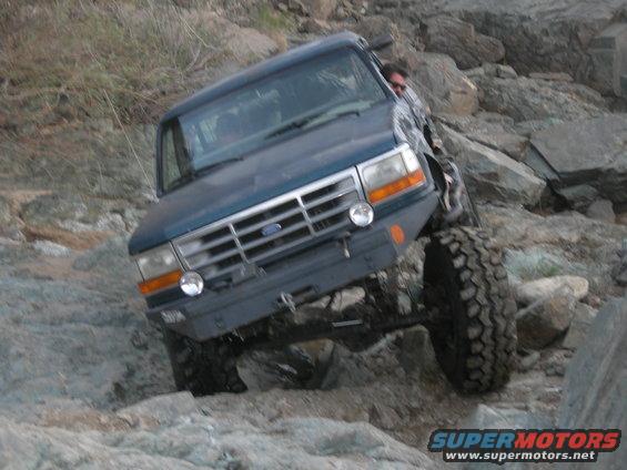 Dark blue Ford Bronco climbing over rocks on a trail