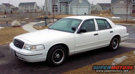 White sedan parked in a driveway with houses in the background