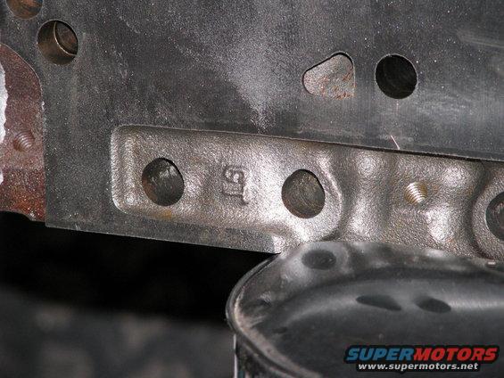 Close-up of cast metal with two bolt holes and the number '15' stamped on it