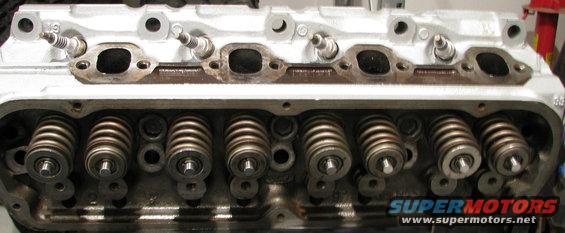 Close-up of an engine cylinder head with spark plugs and valve springs visible